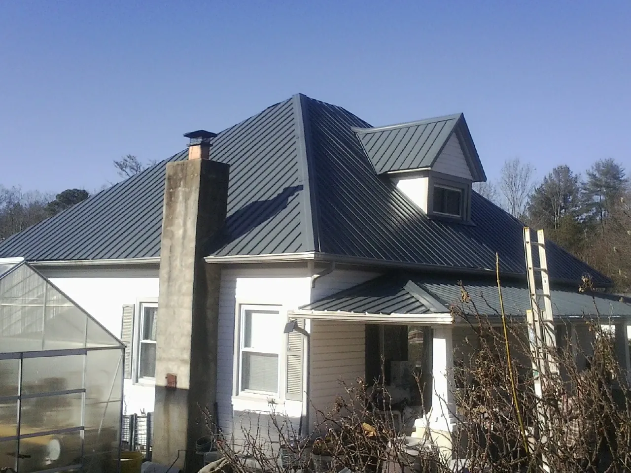 Dark blue standing seam metal roof on a white farmhouse with dormer — Slate & Tile Roof Repair by Roofing Brothers in Lisbon Falls