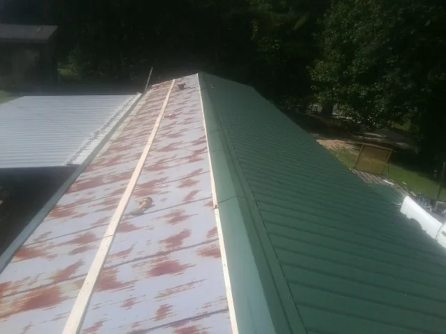Old rusted panels beside newly installed green metal roofing — Wind Damage Roof Repair by Roofing Brothers in Lisbon Falls