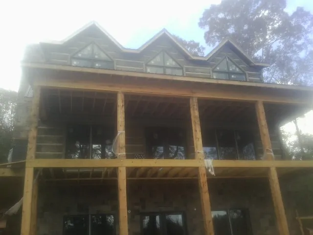 Dormers and porch framing on a large log home under construction — Roof Coating work by our crew in Lisbon Falls