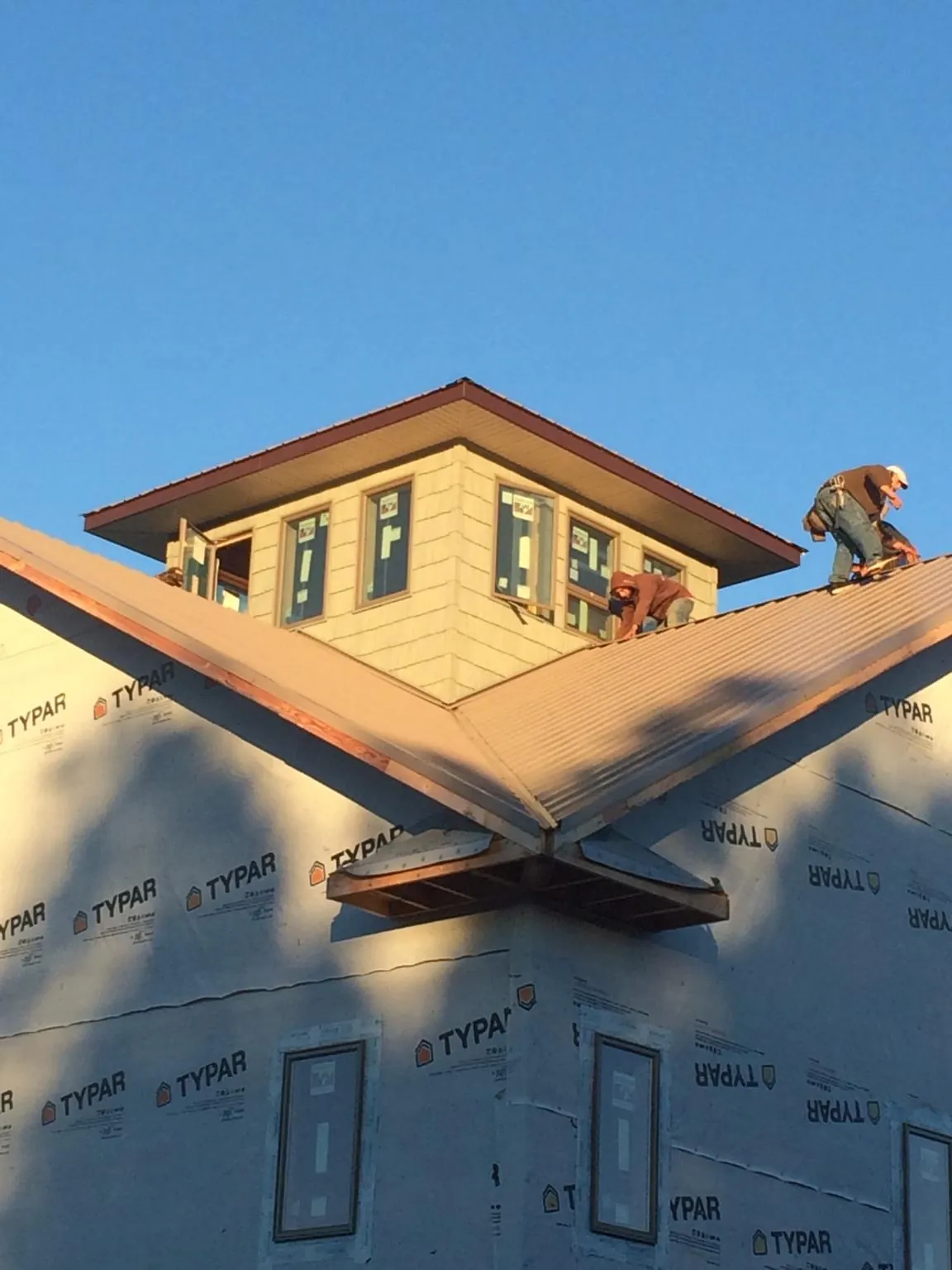 Roofers working around a rooftop cupola on a new metal roof at sunset — Roof Waterproofing in Lisbon Falls by Roofing Brothers